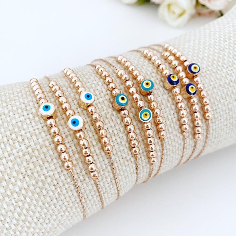 A stunning rose gold Evil Eye Bracelet featuring a minimalist design with a blue, white, or green evil eye charm, adjustable and handmade.