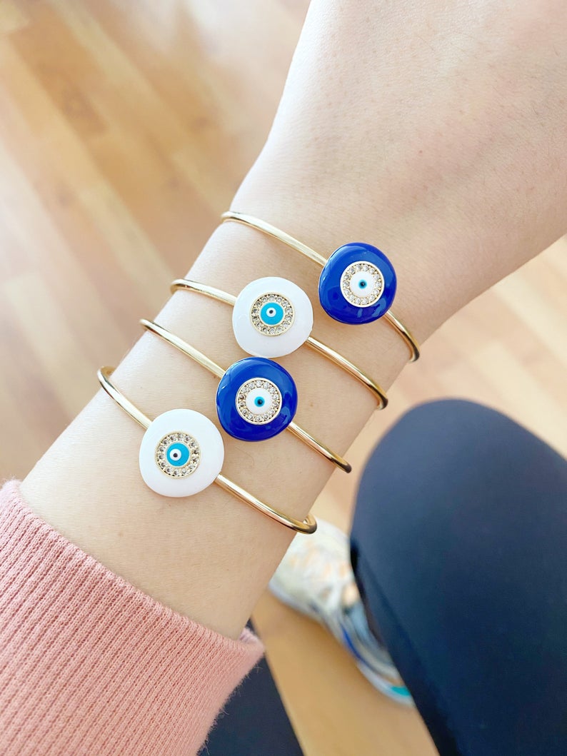 Elegant Evil Eye Bracelet featuring a movable oval charm on a round bangle, available in white and blue colors, made of tarnish-resistant stainless steel.