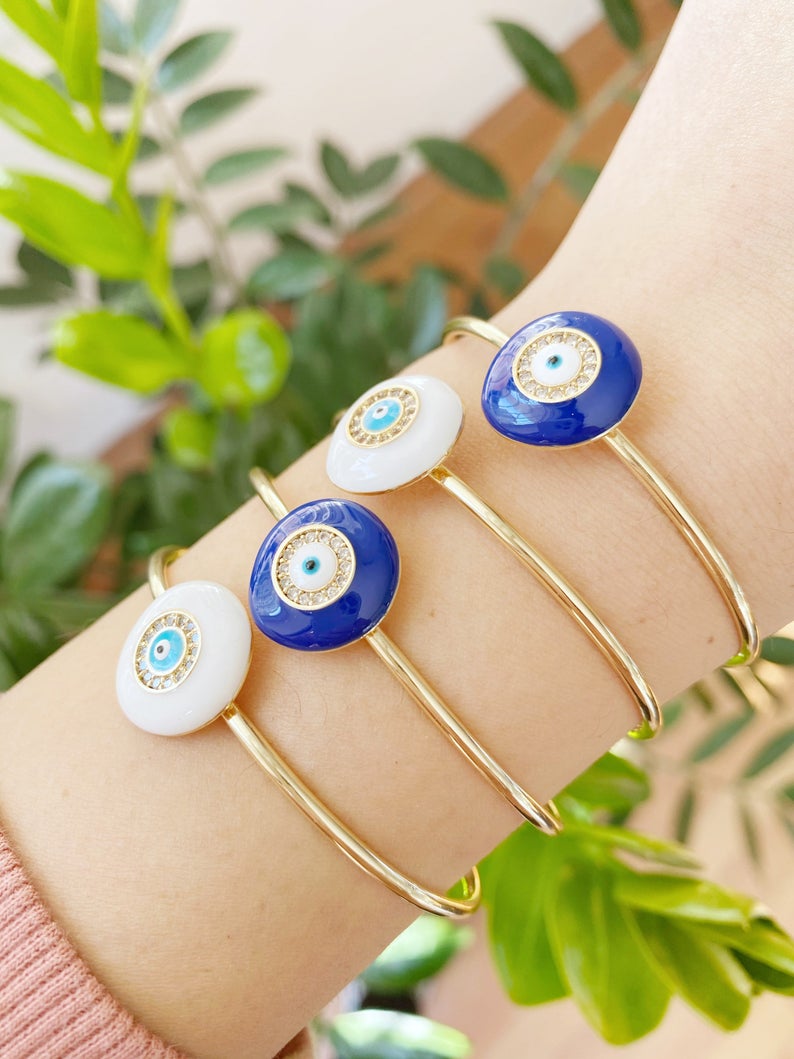 Elegant Evil Eye Bracelet featuring a movable oval charm on a round bangle, available in white and blue colors, made of tarnish-resistant stainless steel.