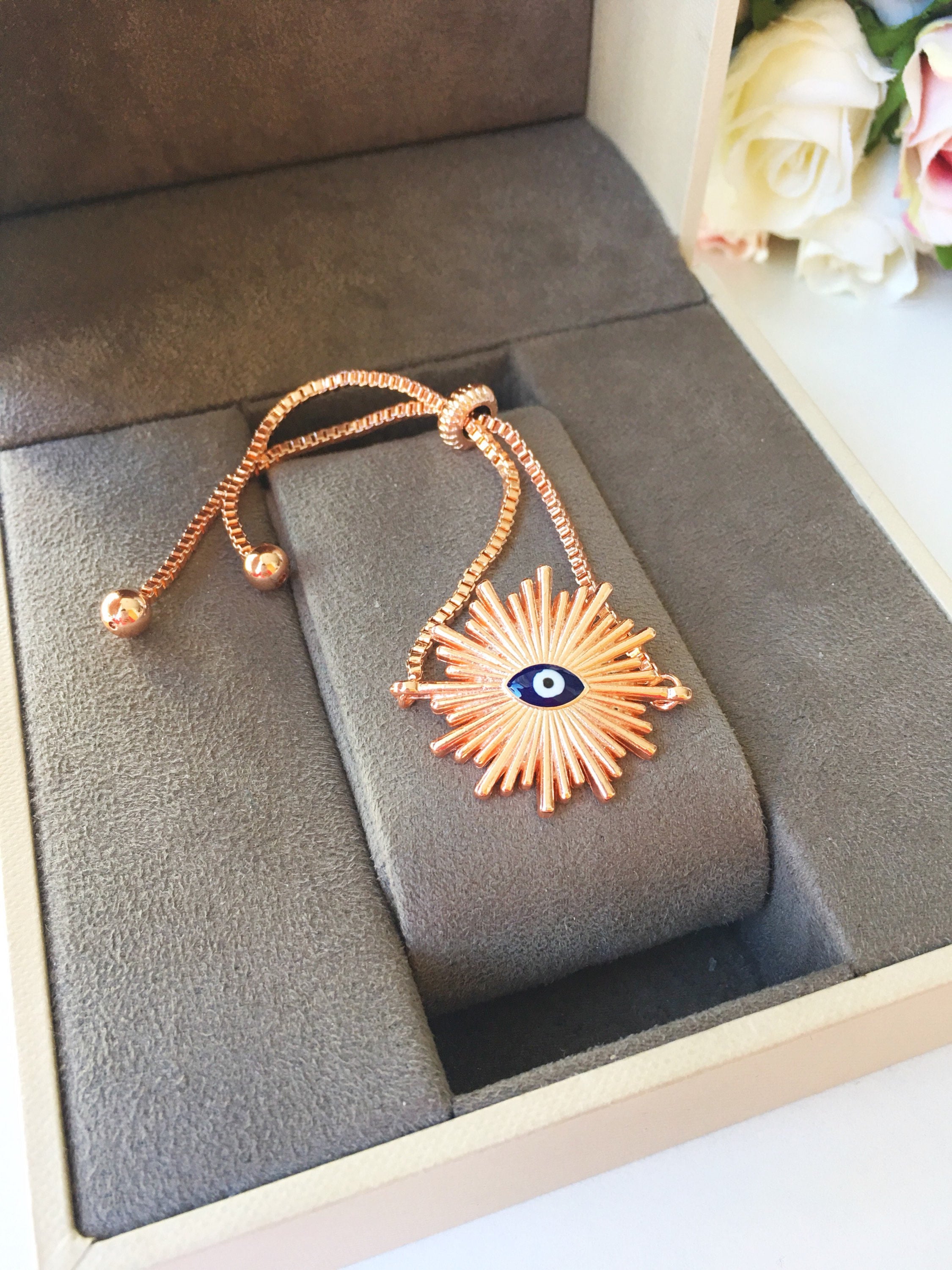 Sunny Charm Evil Eye Bracelet in gold and rose gold, featuring an evil eye charm and adjustable stainless steel chain.