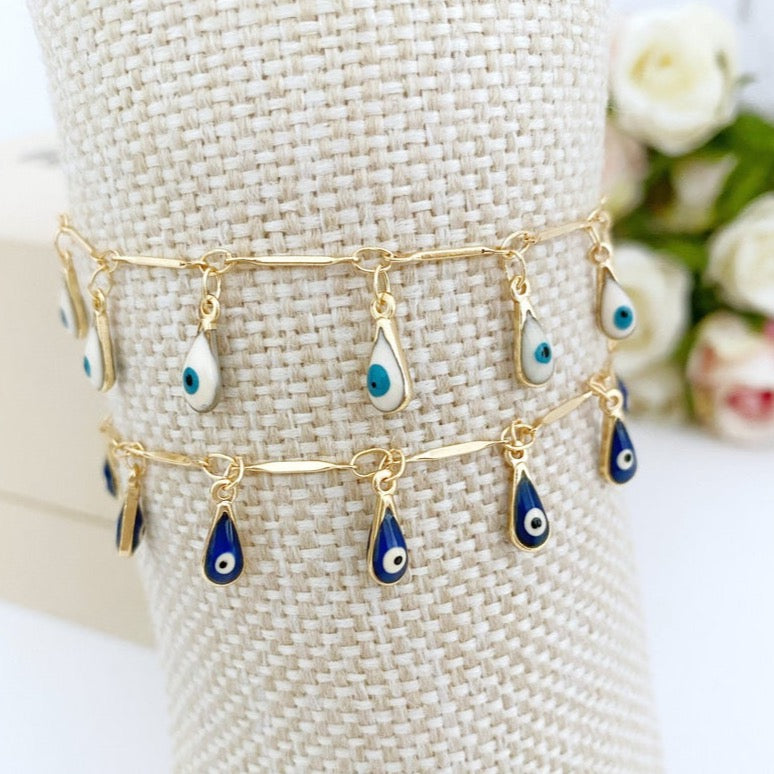 A beautiful Evil Eye Bracelet featuring teardrop blue and white beads on a gold chain, symbolizing protection and style.