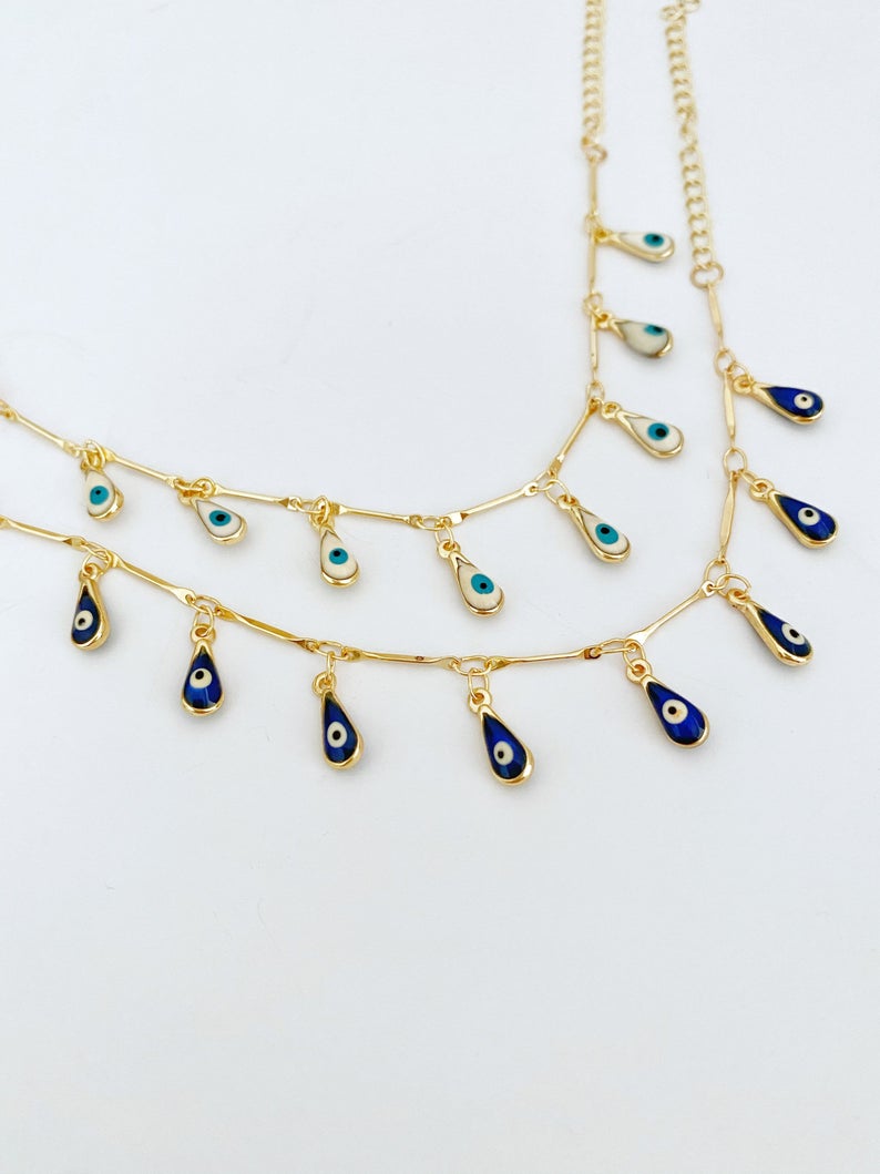 A beautiful Evil Eye Bracelet featuring teardrop blue and white beads on a gold chain, symbolizing protection and style.