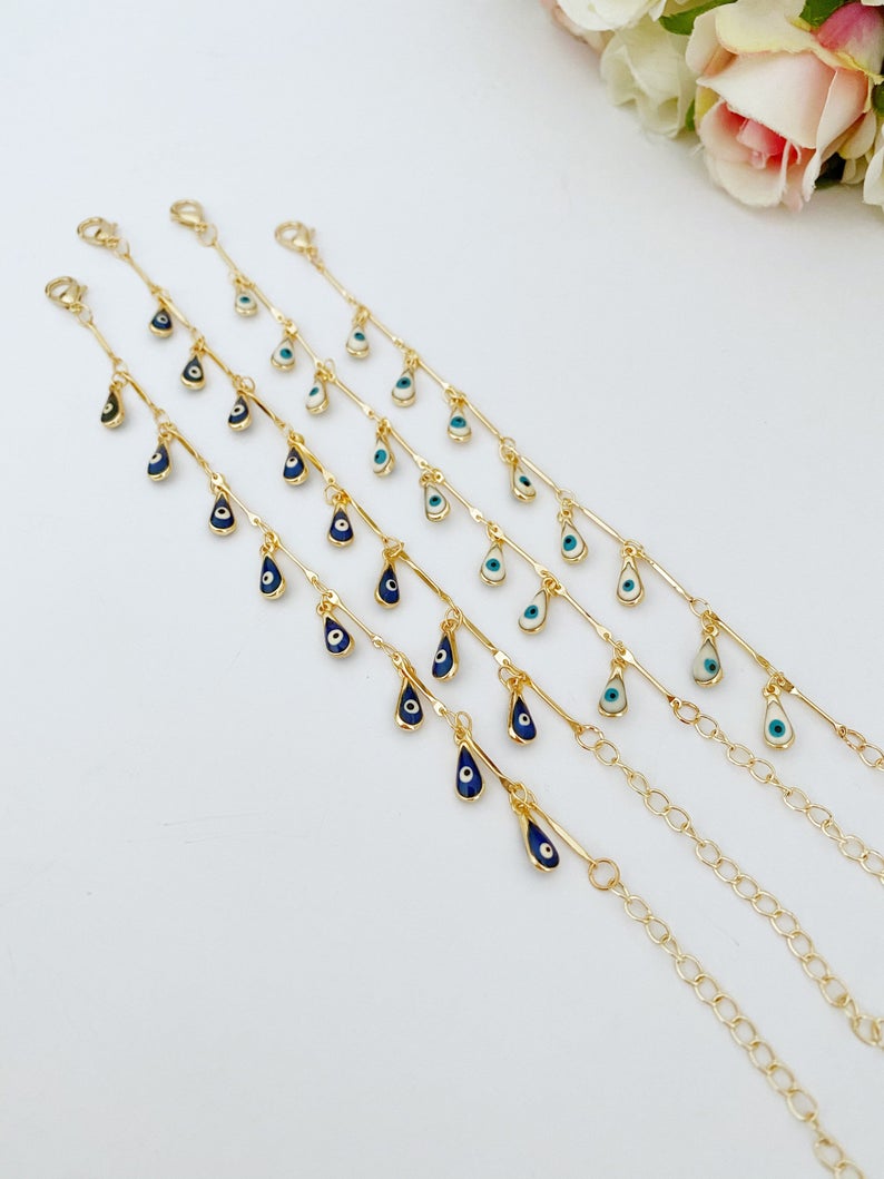 A beautiful Evil Eye Bracelet featuring teardrop blue and white beads on a gold chain, symbolizing protection and style.