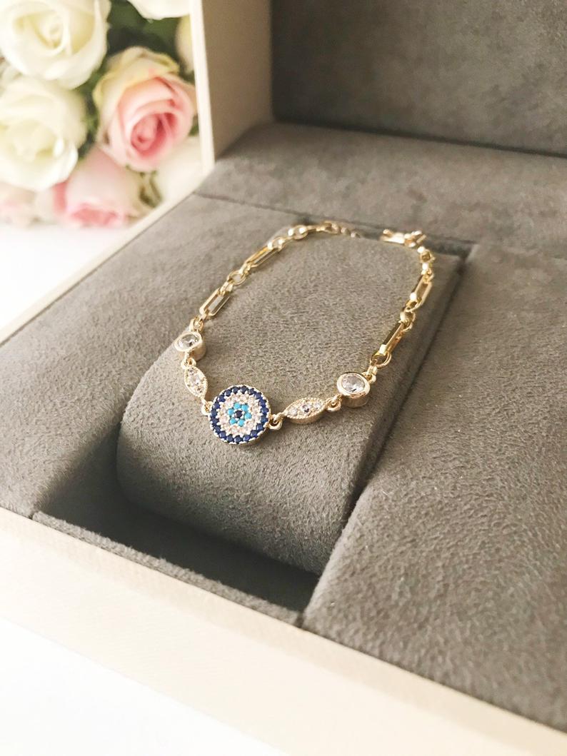 Elegant Evil Eye Bracelet featuring a zircon charm on a gold chain, showcasing a blue evil eye bead.