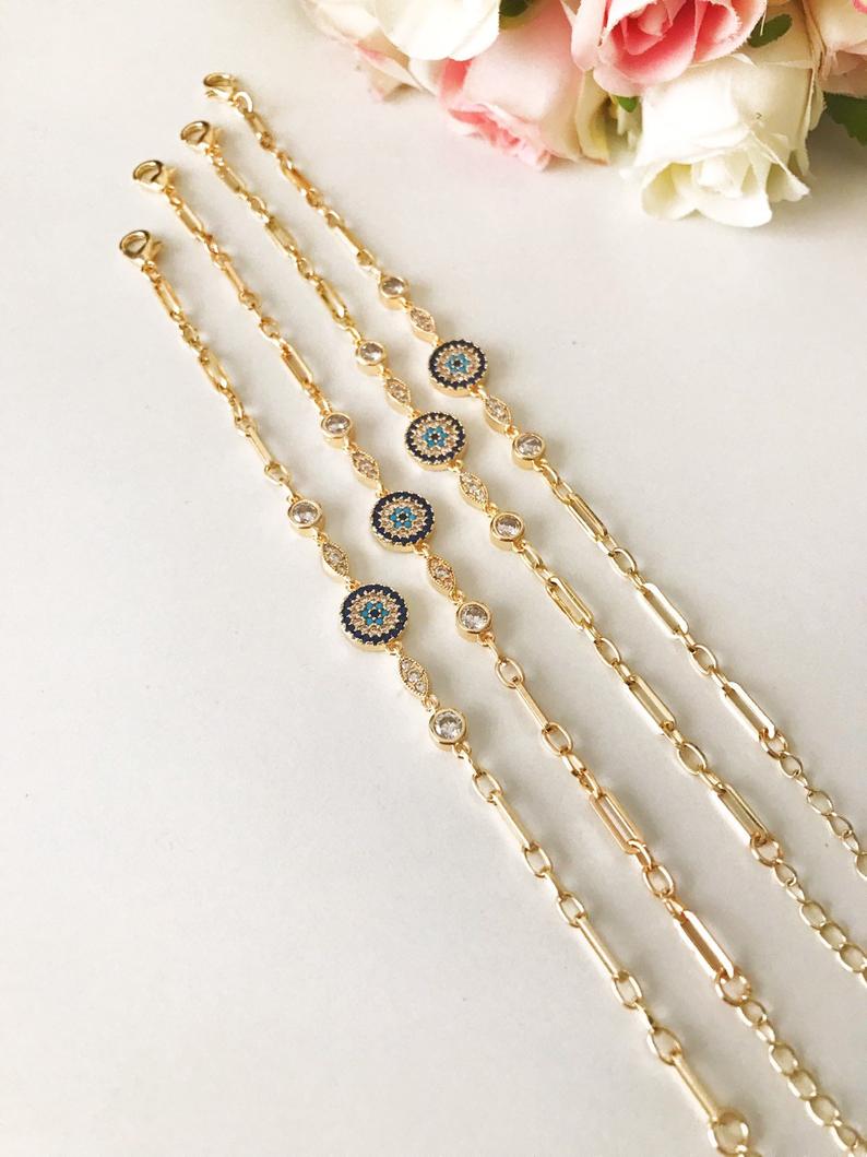 Elegant Evil Eye Bracelet featuring a zircon charm on a gold chain, showcasing a blue evil eye bead.