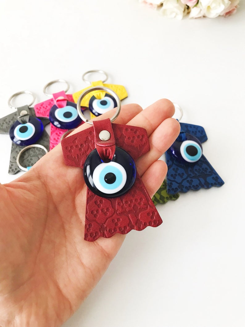 Evil eye caftan keychain featuring a suede leather tulip shape and a glass evil eye bead, available in various colors.