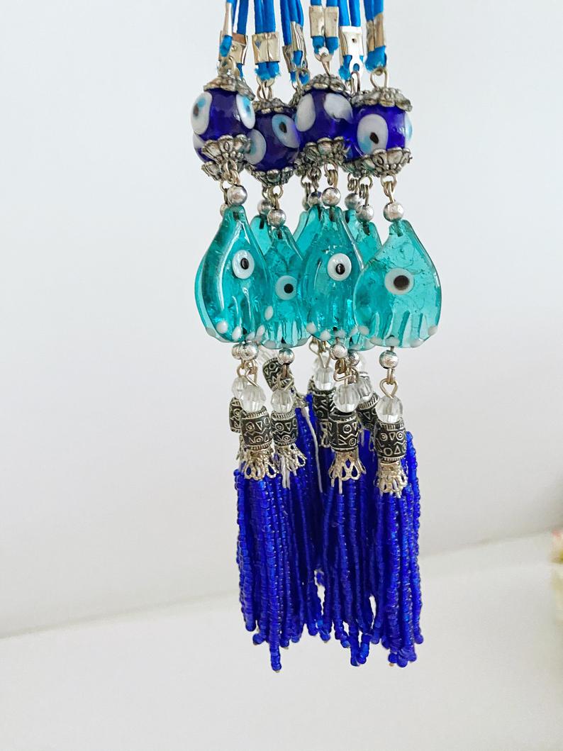 Handmade Evil Eye Car Charm featuring a Hamsa Hand design, made of glass beads, hanging from a rearview mirror.