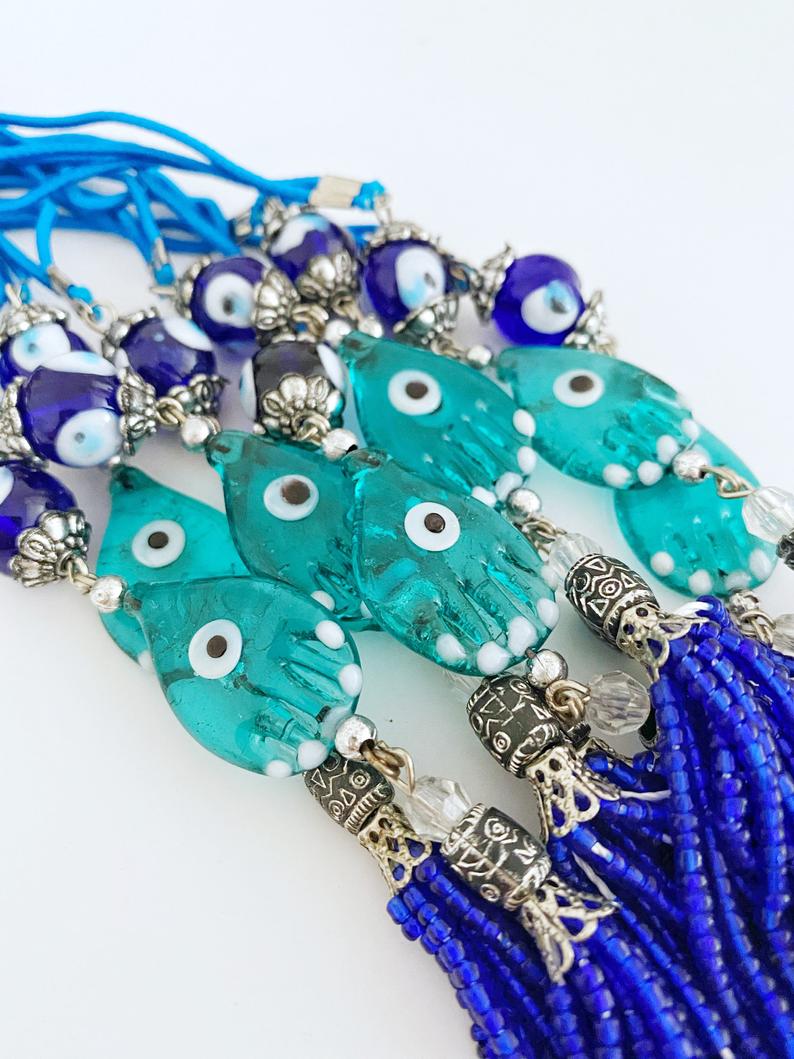 Handmade Evil Eye Car Charm featuring a Hamsa Hand design, made of glass beads, hanging from a rearview mirror.