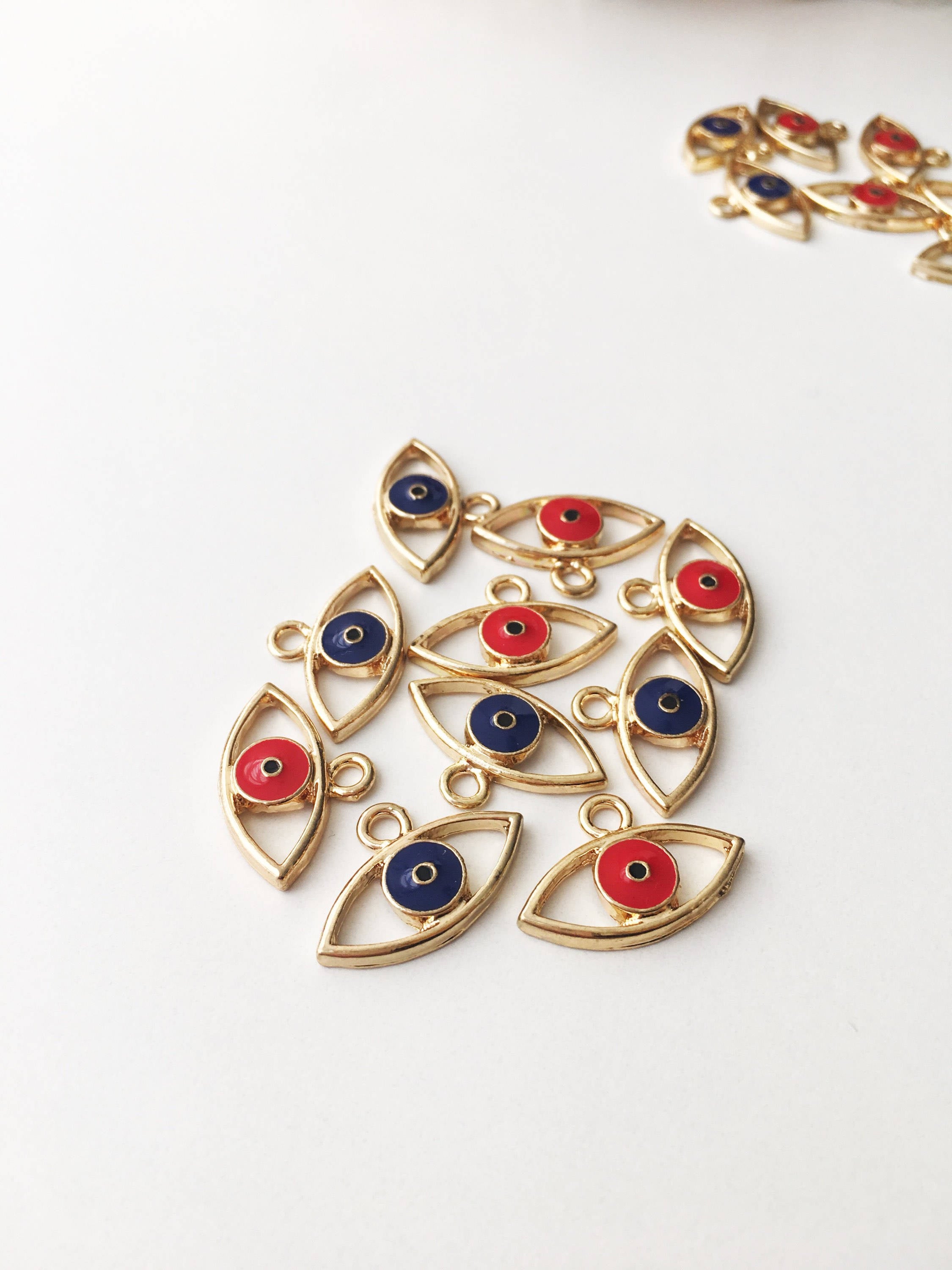 Two brass evil eye charms in blue and red, featuring intricate designs symbolizing protection and good luck.