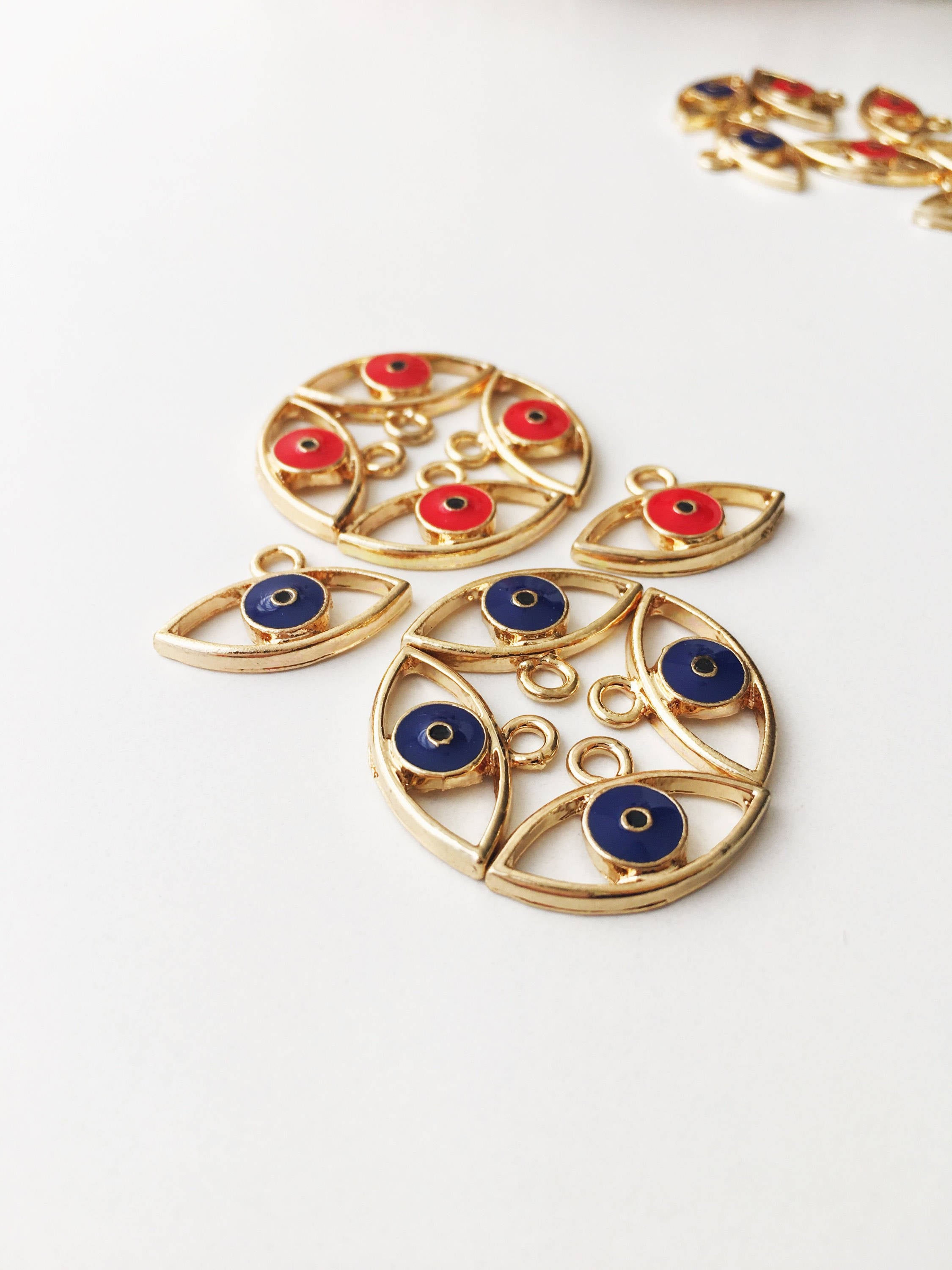 Two brass evil eye charms in blue and red, featuring intricate designs symbolizing protection and good luck.