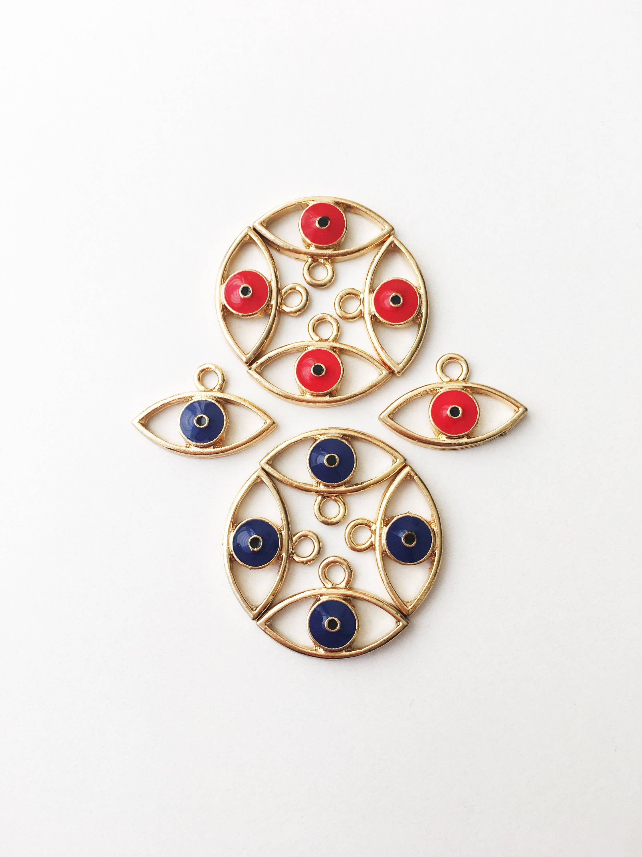 Two brass evil eye charms in blue and red, featuring intricate designs symbolizing protection and good luck.