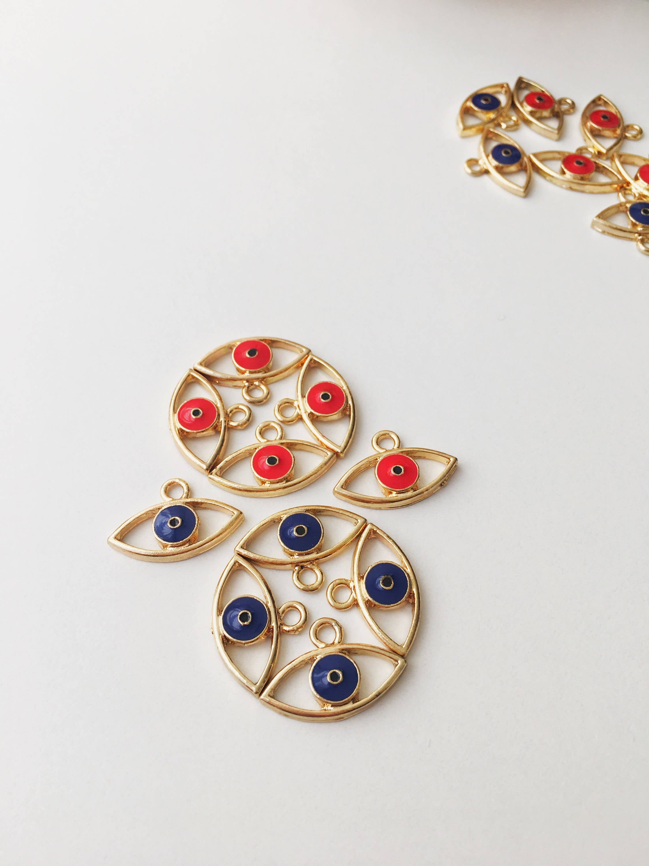 Two brass evil eye charms in blue and red, featuring intricate designs symbolizing protection and good luck.