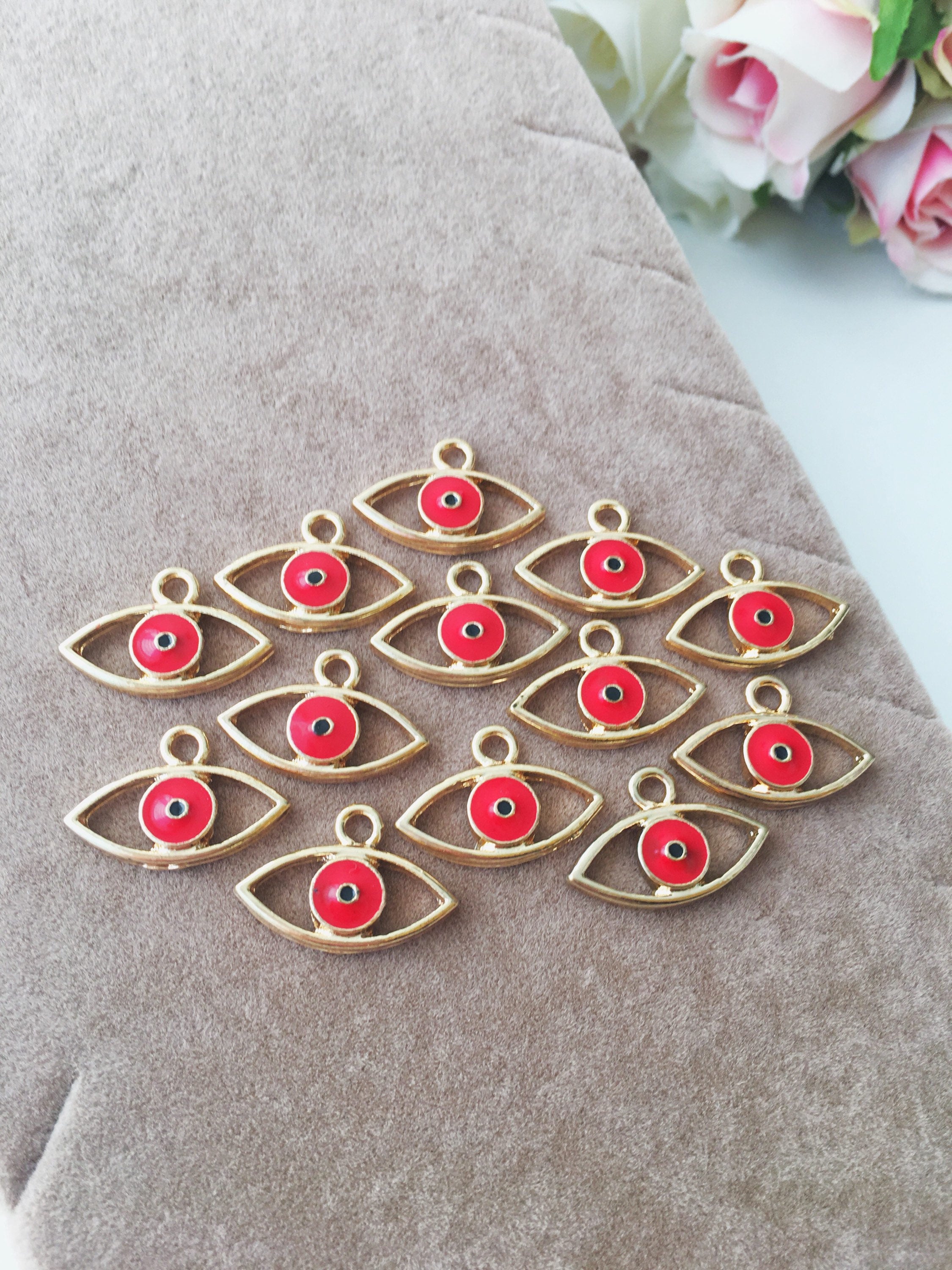 Two brass evil eye charms in blue and red, featuring intricate designs symbolizing protection and good luck.