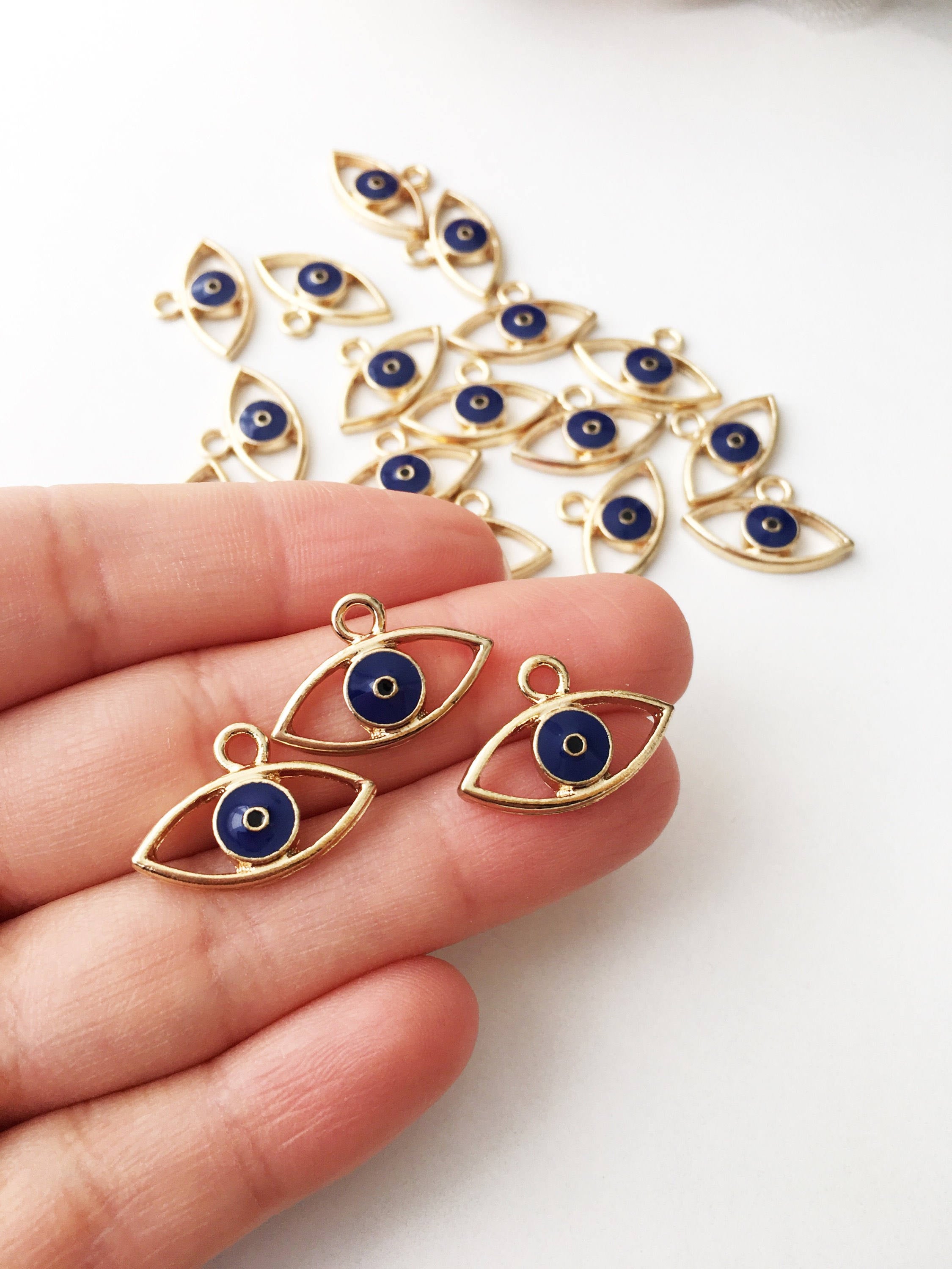 Two brass evil eye charms in blue and red, featuring intricate designs symbolizing protection and good luck.