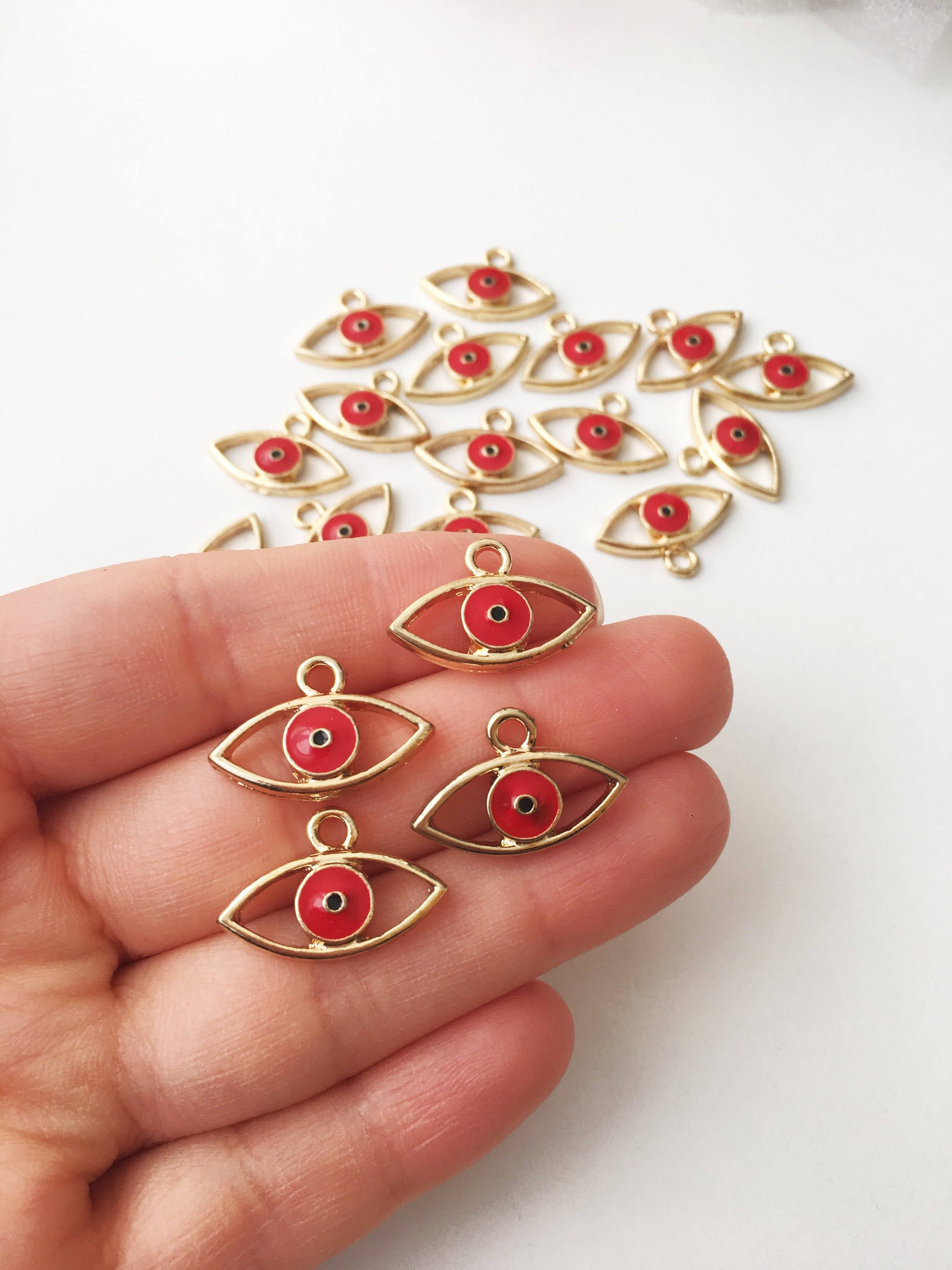 Two brass evil eye charms in blue and red, featuring intricate designs symbolizing protection and good luck.