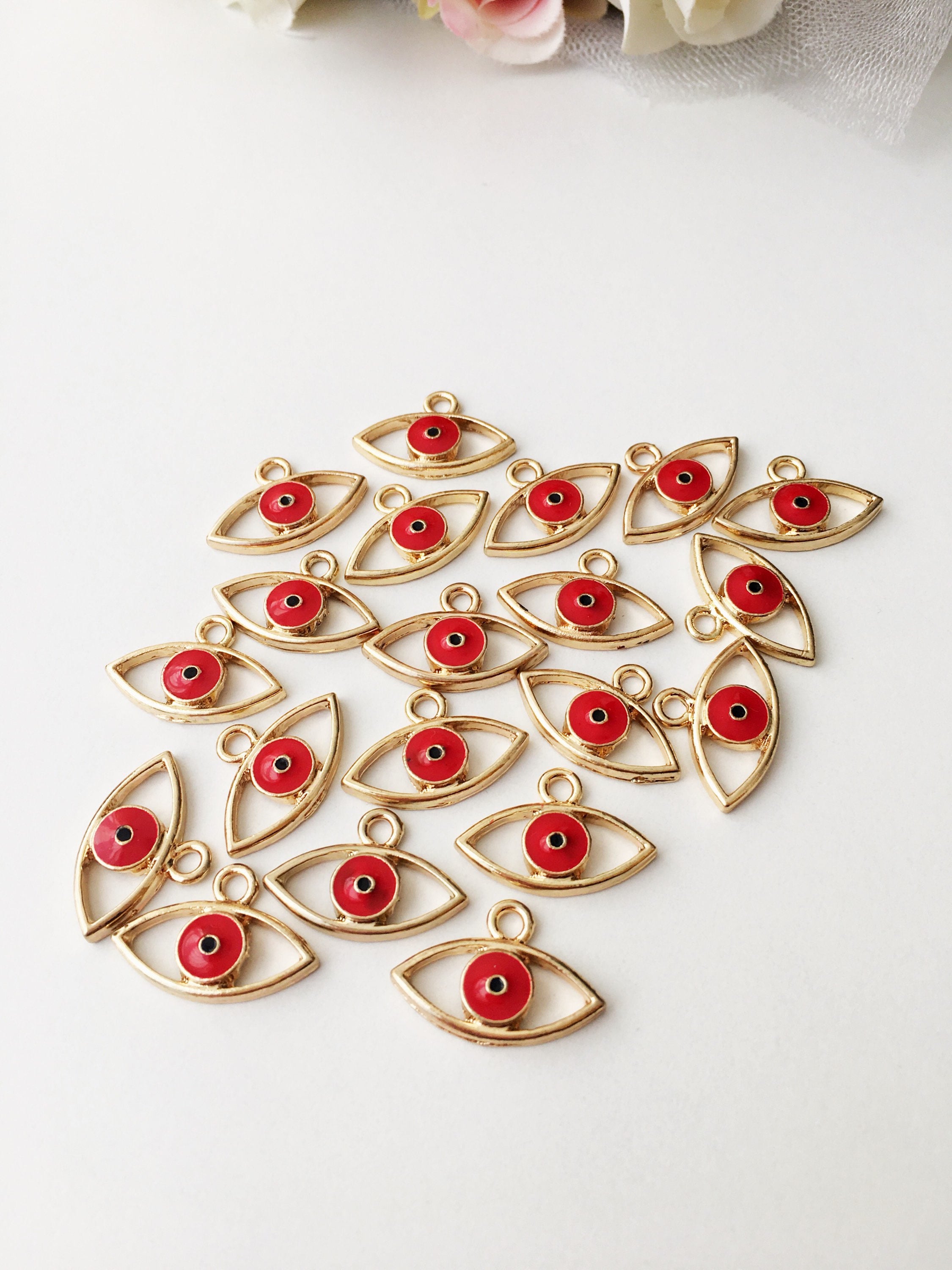 Two brass evil eye charms in blue and red, featuring intricate designs symbolizing protection and good luck.