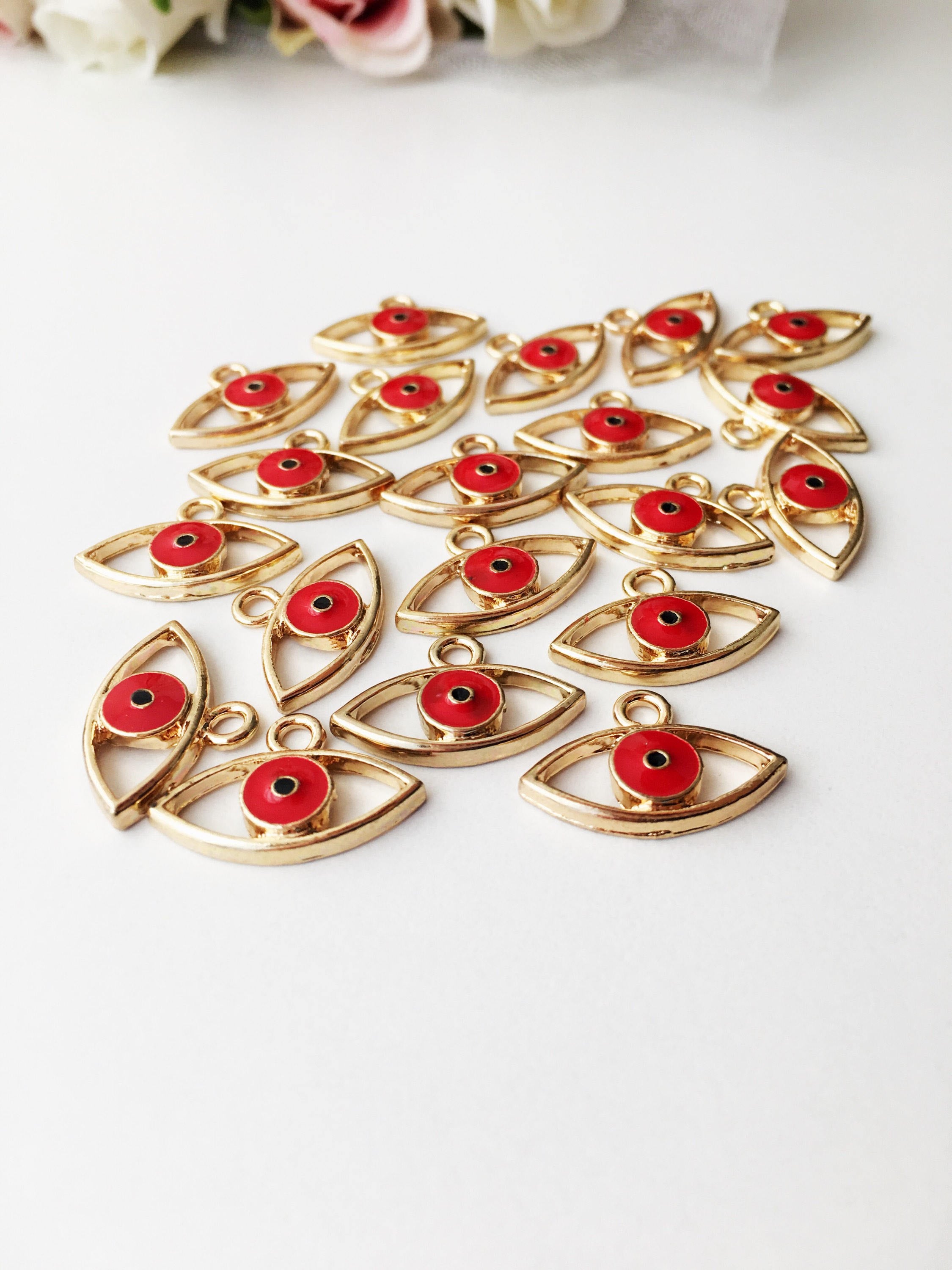 Two brass evil eye charms in blue and red, featuring intricate designs symbolizing protection and good luck.