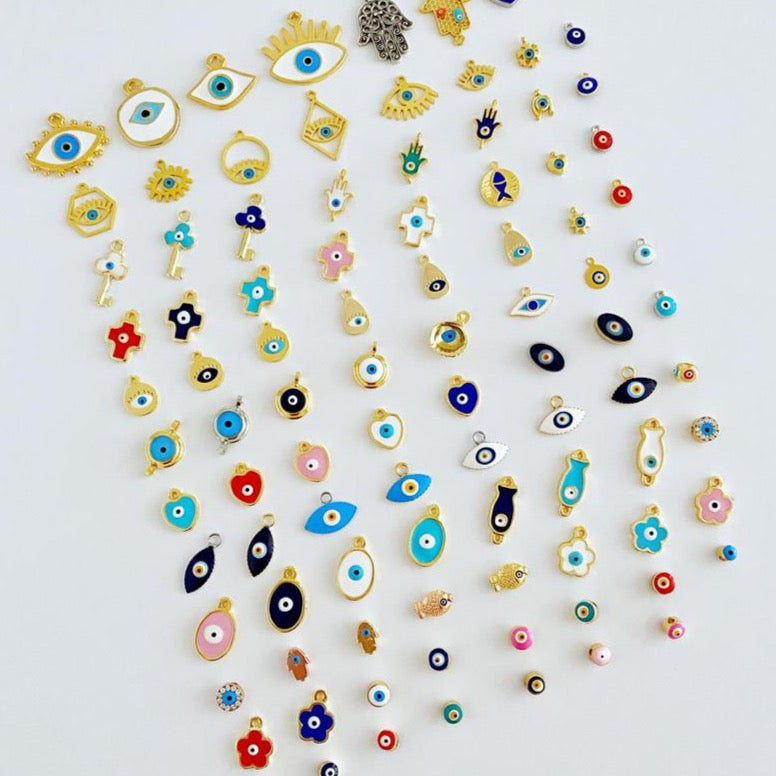 A collection of brass evil eye charms in various styles, showcasing blue and colorful designs for jewelry making.