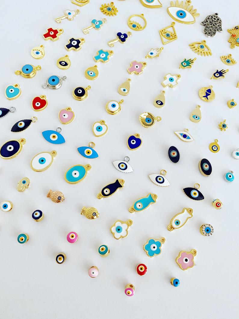 A collection of brass evil eye charms in various styles, showcasing blue and colorful designs for jewelry making.