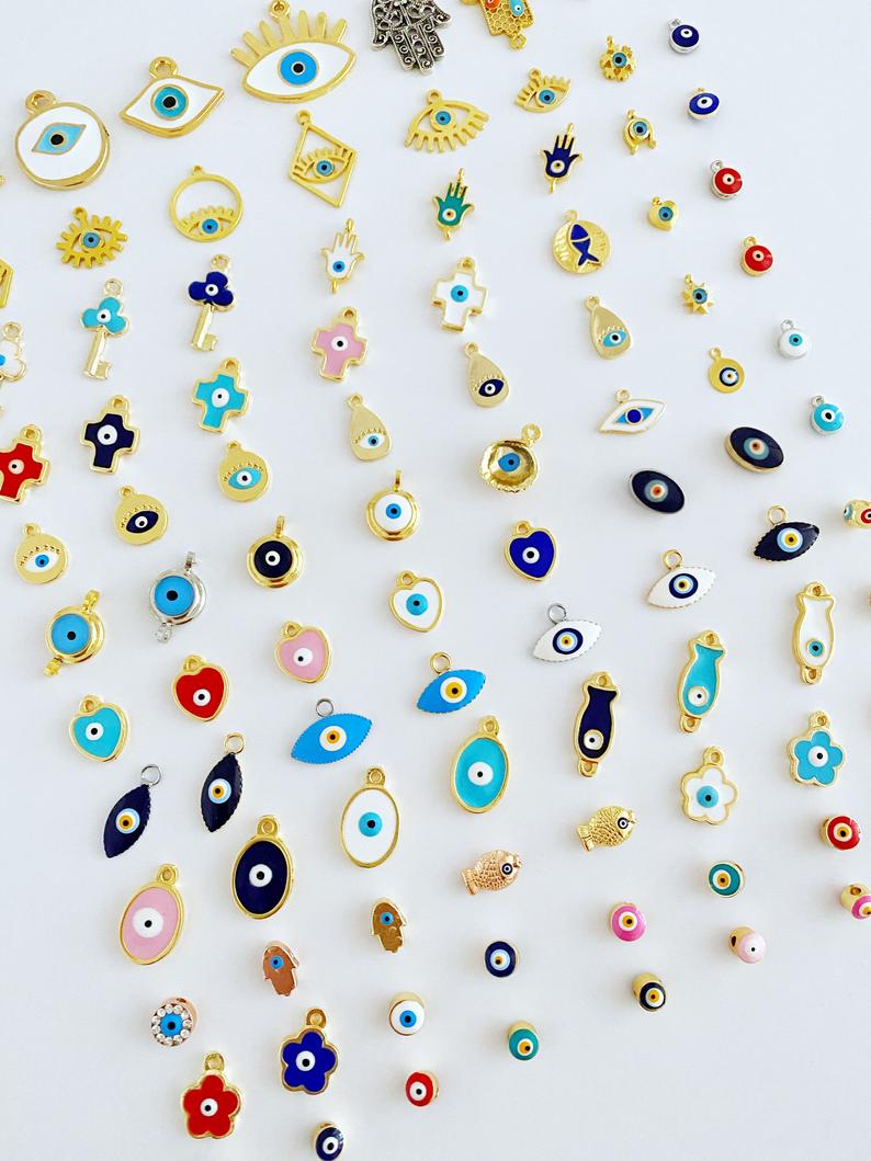 A collection of brass evil eye charms in various styles, showcasing blue and colorful designs for jewelry making.