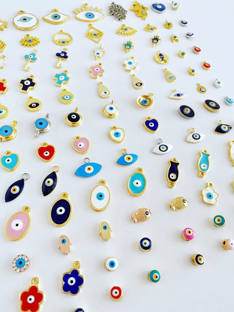 A collection of brass evil eye charms in various styles, showcasing blue and colorful designs for jewelry making.