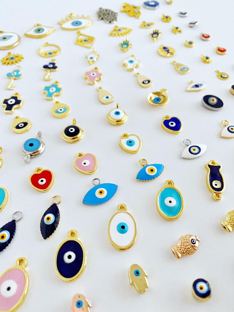 A collection of brass evil eye charms in various styles, showcasing blue and colorful designs for jewelry making.