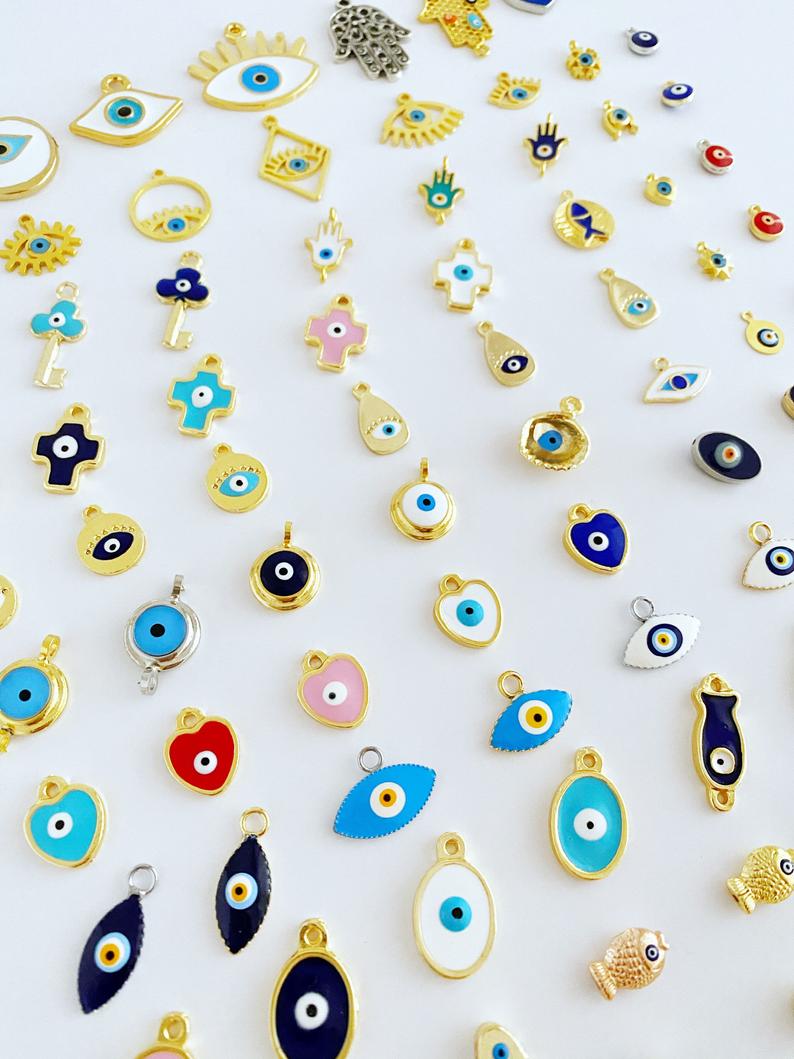 A collection of brass evil eye charms in various styles, showcasing blue and colorful designs for jewelry making.