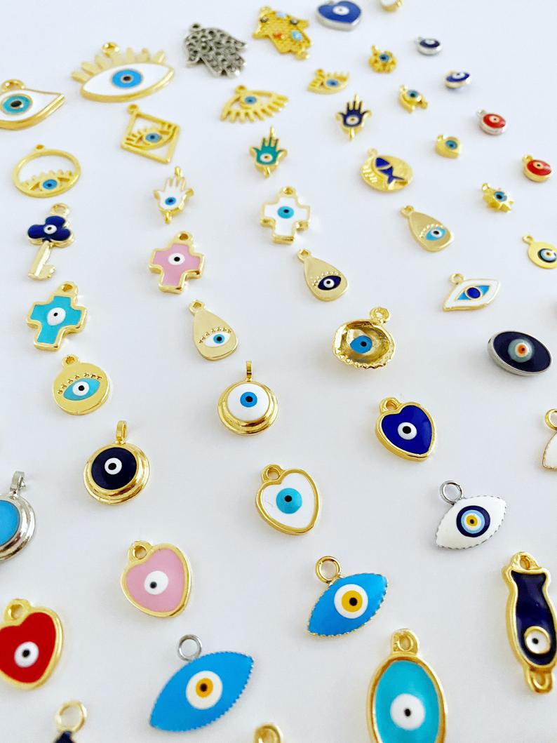 A collection of brass evil eye charms in various styles, showcasing blue and colorful designs for jewelry making.