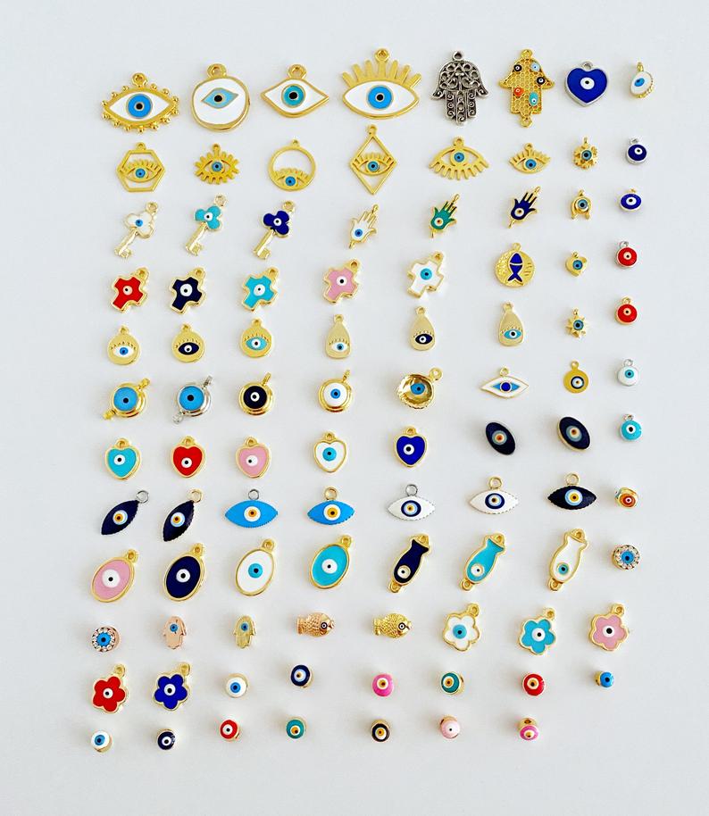 A collection of brass evil eye charms in various styles, showcasing blue and colorful designs for jewelry making.