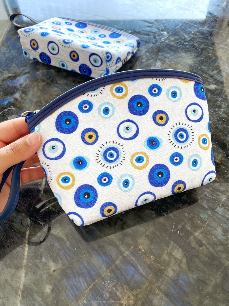 A stylish white Evil Eye Clutch Bag featuring a unique evil eye design, perfect for makeup, travel, and everyday use.