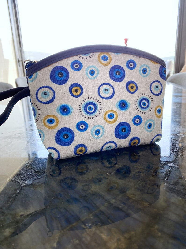 A stylish white Evil Eye Clutch Bag featuring a unique evil eye design, perfect for makeup, travel, and everyday use.