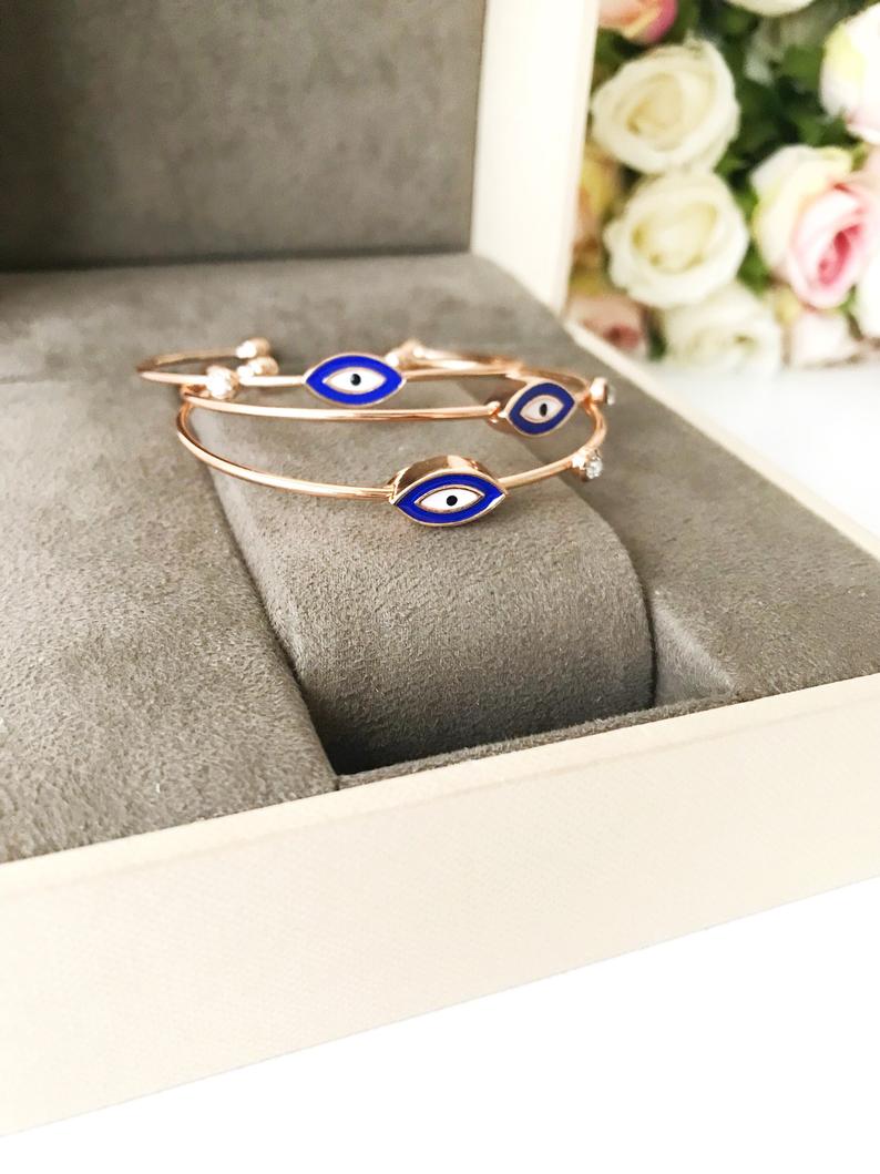 Evil Eye Cuff Bracelet featuring a movable blue and white charm on a rose gold bangle, showcasing its elegant design and adjustable size.