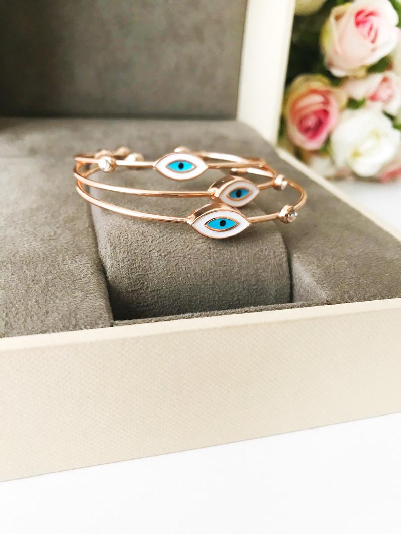 Evil Eye Cuff Bracelet featuring a movable blue and white charm on a rose gold bangle, showcasing its elegant design and adjustable size.