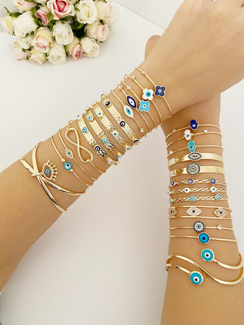 Gold Evil Eye Cuff Bracelet featuring a movable oval charm and round bangle design, showcasing intricate craftsmanship.