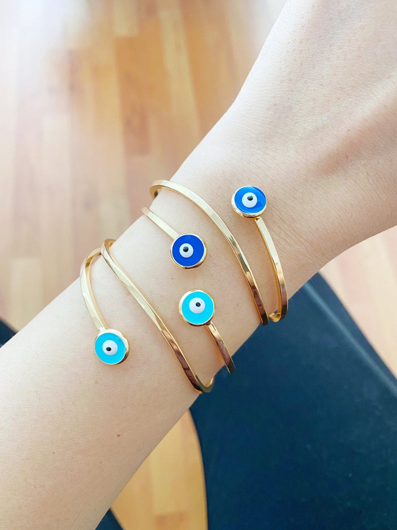 Gold Evil Eye Cuff Bracelet featuring a movable oval charm and adjustable stainless steel design, perfect for stylish protection.