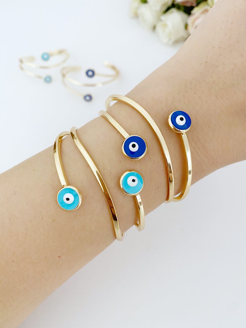 Gold Evil Eye Cuff Bracelet featuring a movable oval charm and adjustable stainless steel design, perfect for stylish protection.