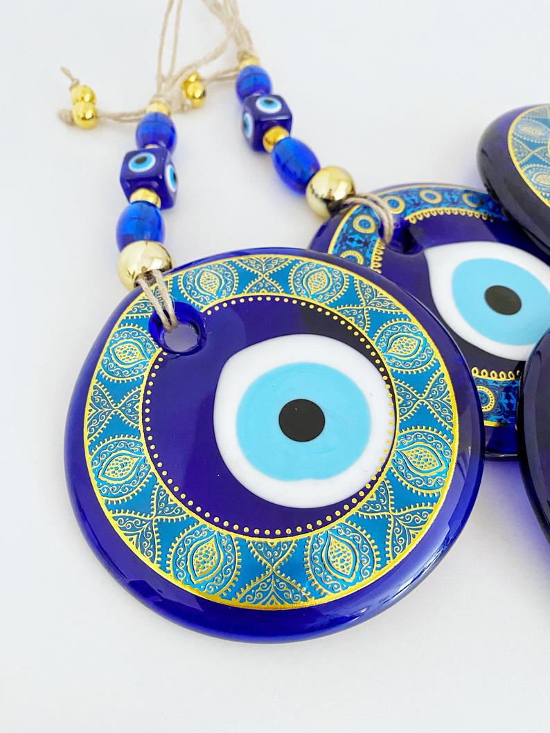 A beautifully hand-painted 11cm Evil Eye wall hanging featuring intricate blue patterns, symbolizing protection and good fortune.