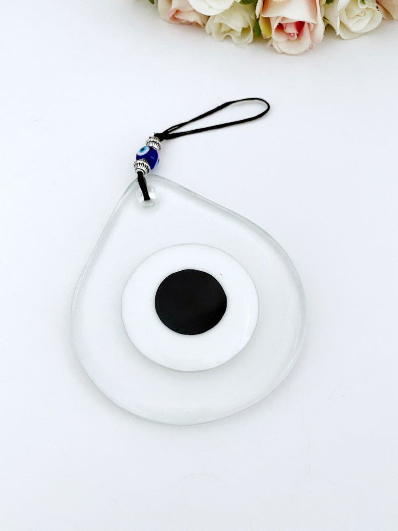 Handmade clear glass Evil Eye bead wall hanging, symbolizing protection and good luck, featuring a unique design.