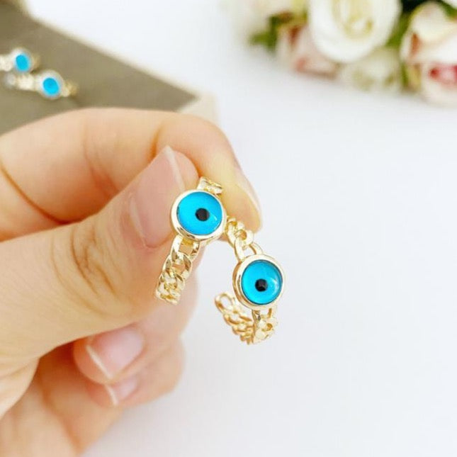 A pair of handmade chunky gold hoop earrings featuring a dainty blue evil eye bead, symbolizing protection and style.