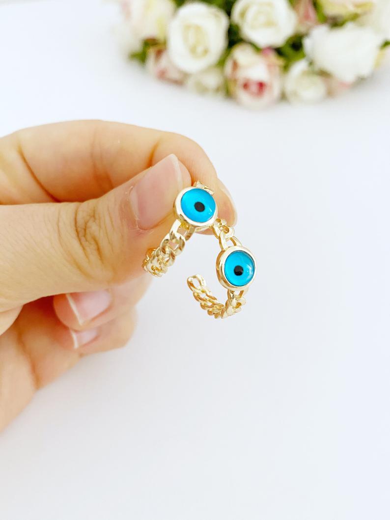 A pair of handmade chunky gold hoop earrings featuring a dainty blue evil eye bead, symbolizing protection and style.