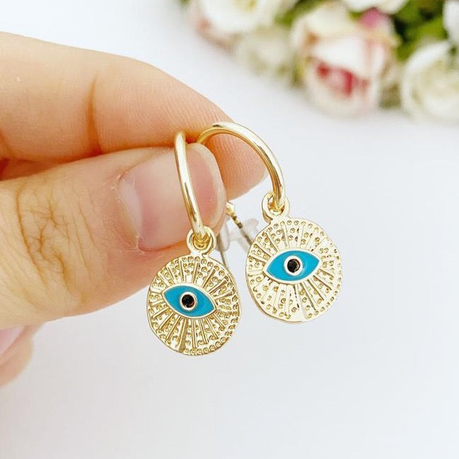 A pair of elegant gold hoop earrings featuring a unique evil eye charm, handcrafted with a hammered texture for added shine.