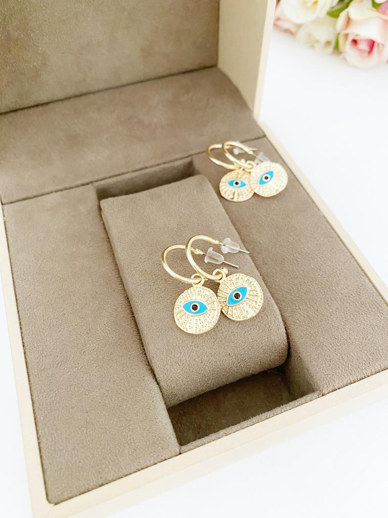 A pair of elegant gold hoop earrings featuring a unique evil eye charm, handcrafted with a hammered texture for added shine.