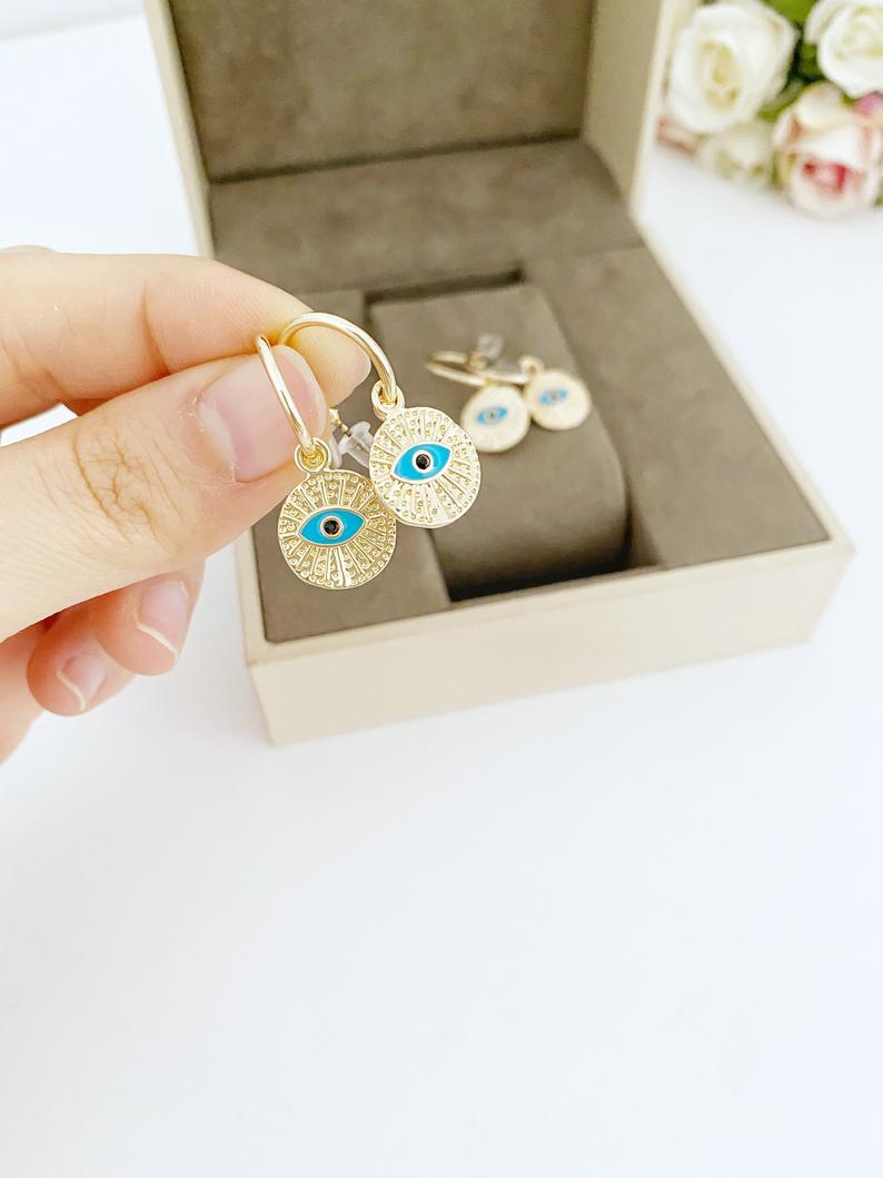 A pair of elegant gold hoop earrings featuring a unique evil eye charm, handcrafted with a hammered texture for added shine.