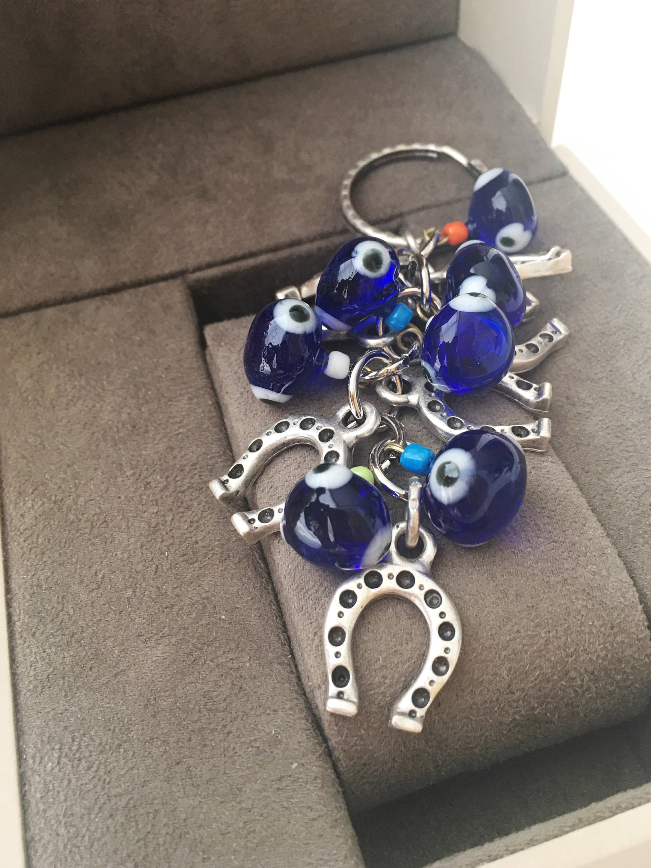 Evil eye horseshoe charm keychain featuring a blue glass evil eye and silver plated horseshoe, symbolizing good luck and protection.