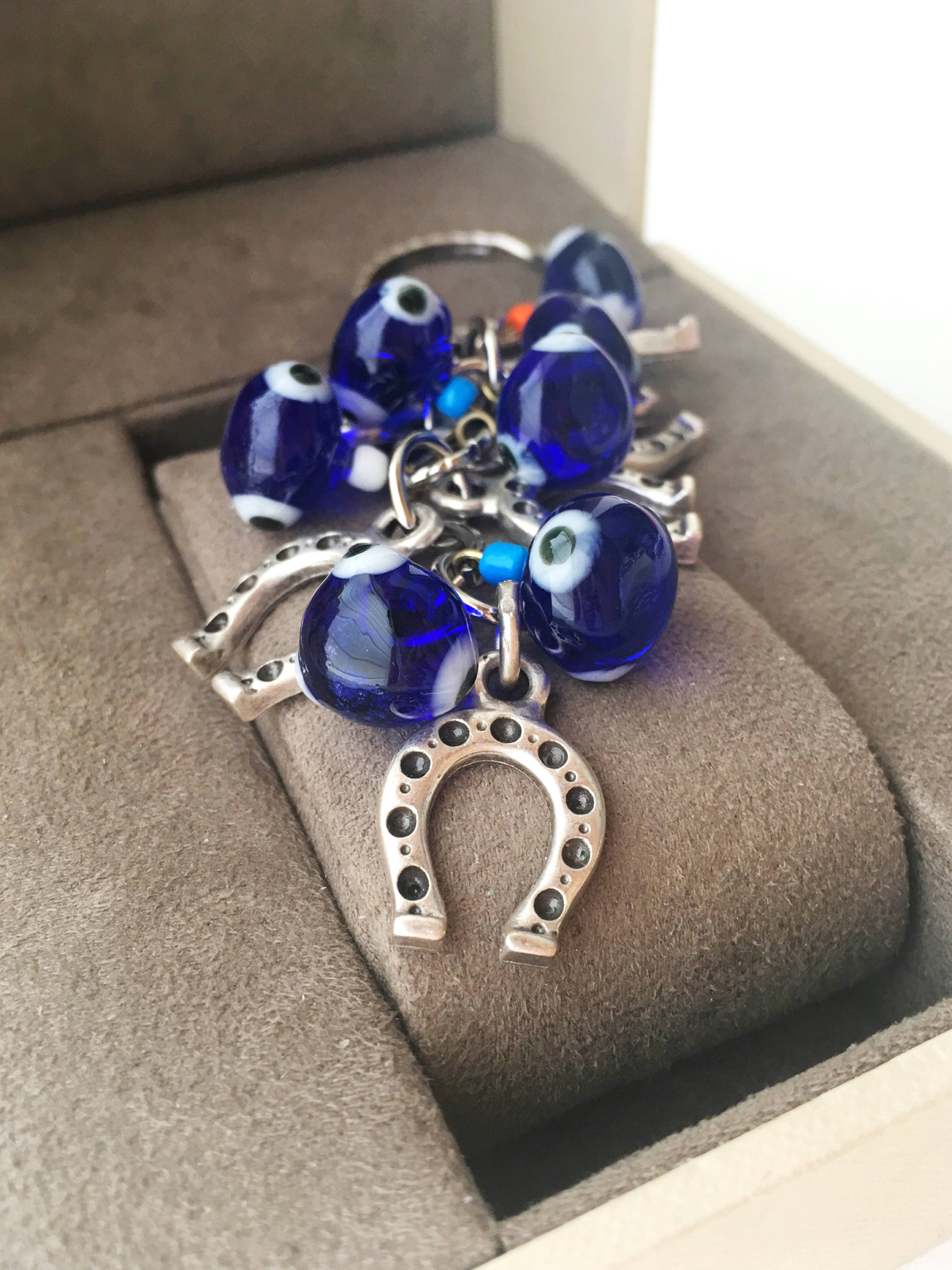 Evil eye horseshoe charm keychain featuring a blue glass evil eye and silver plated horseshoe, symbolizing good luck and protection.