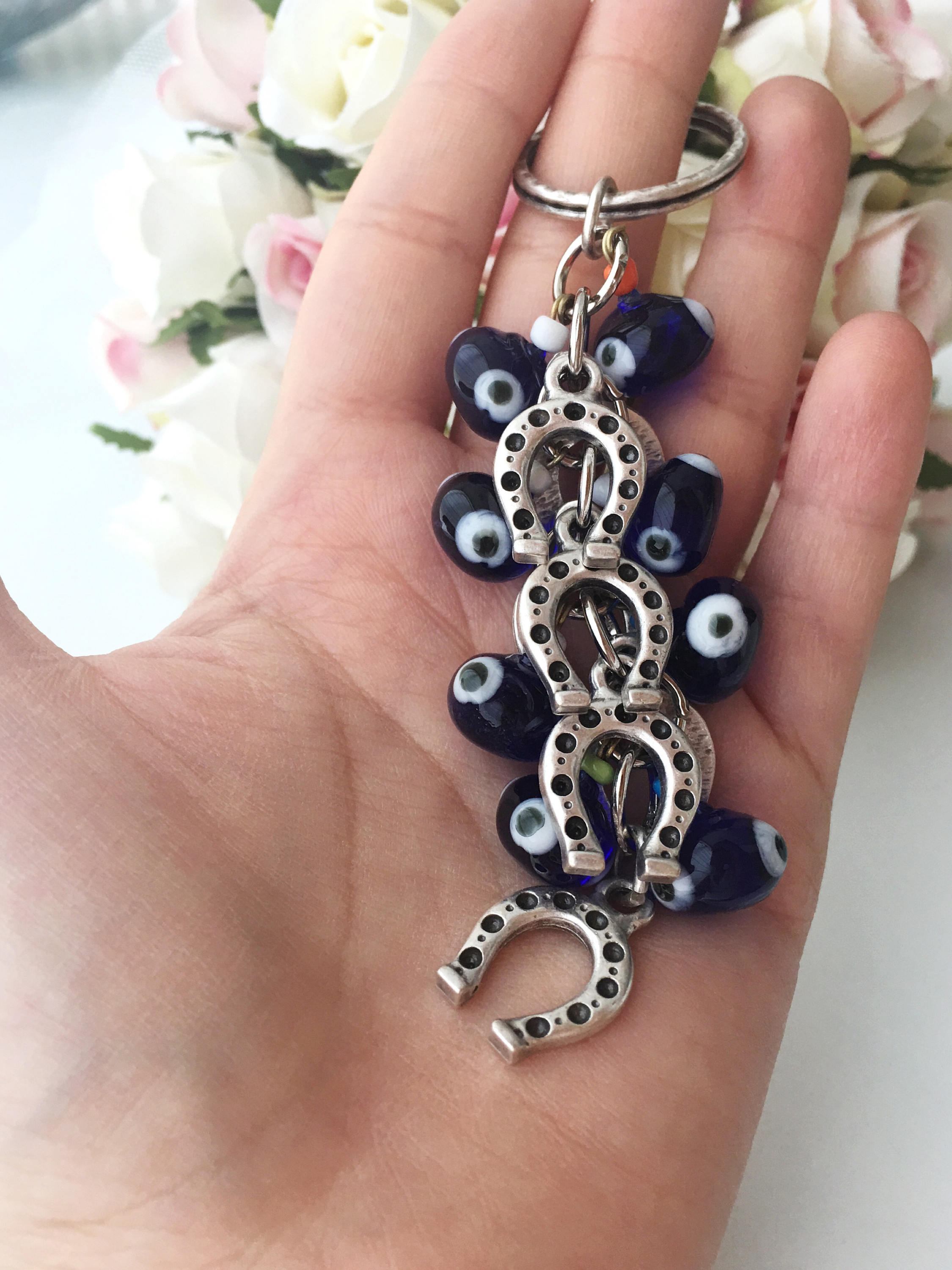 Evil eye horseshoe charm keychain featuring a blue glass evil eye and silver plated horseshoe, symbolizing good luck and protection.