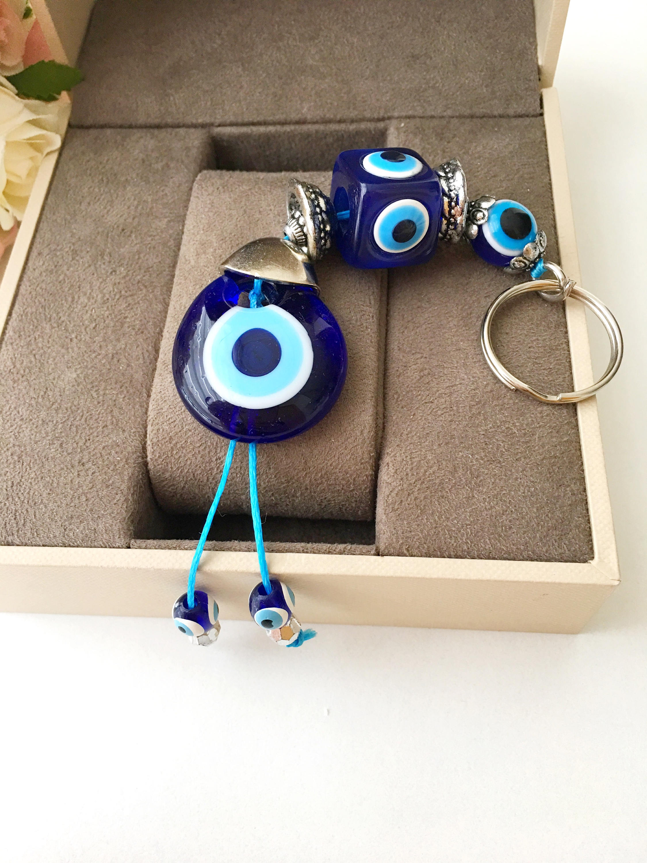 A beautifully crafted Evil Eye keychain featuring vibrant blue and white beads, symbolizing protection and good luck, attached to a silver keyring.