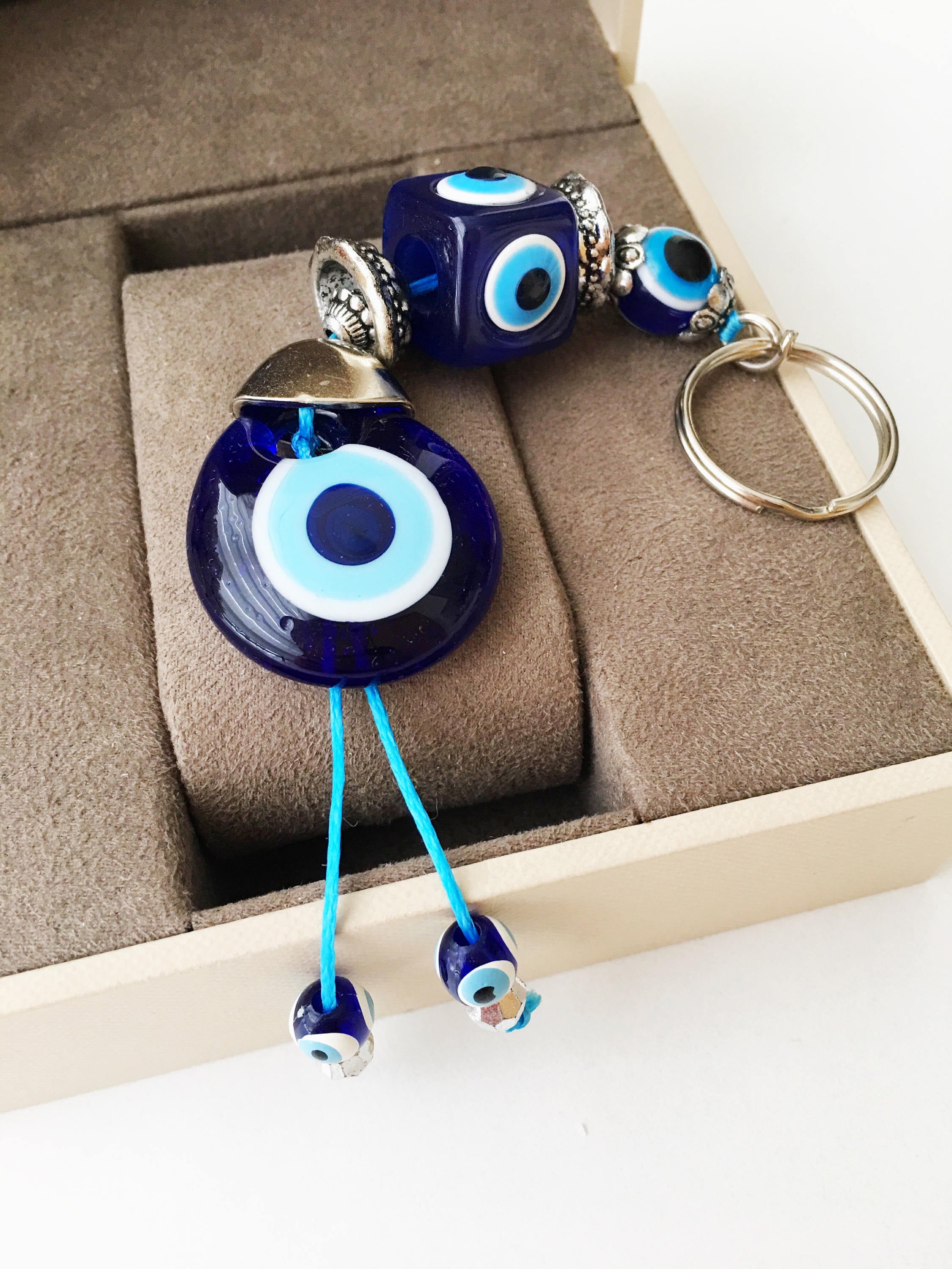 A beautifully crafted Evil Eye keychain featuring vibrant blue and white beads, symbolizing protection and good luck, attached to a silver keyring.