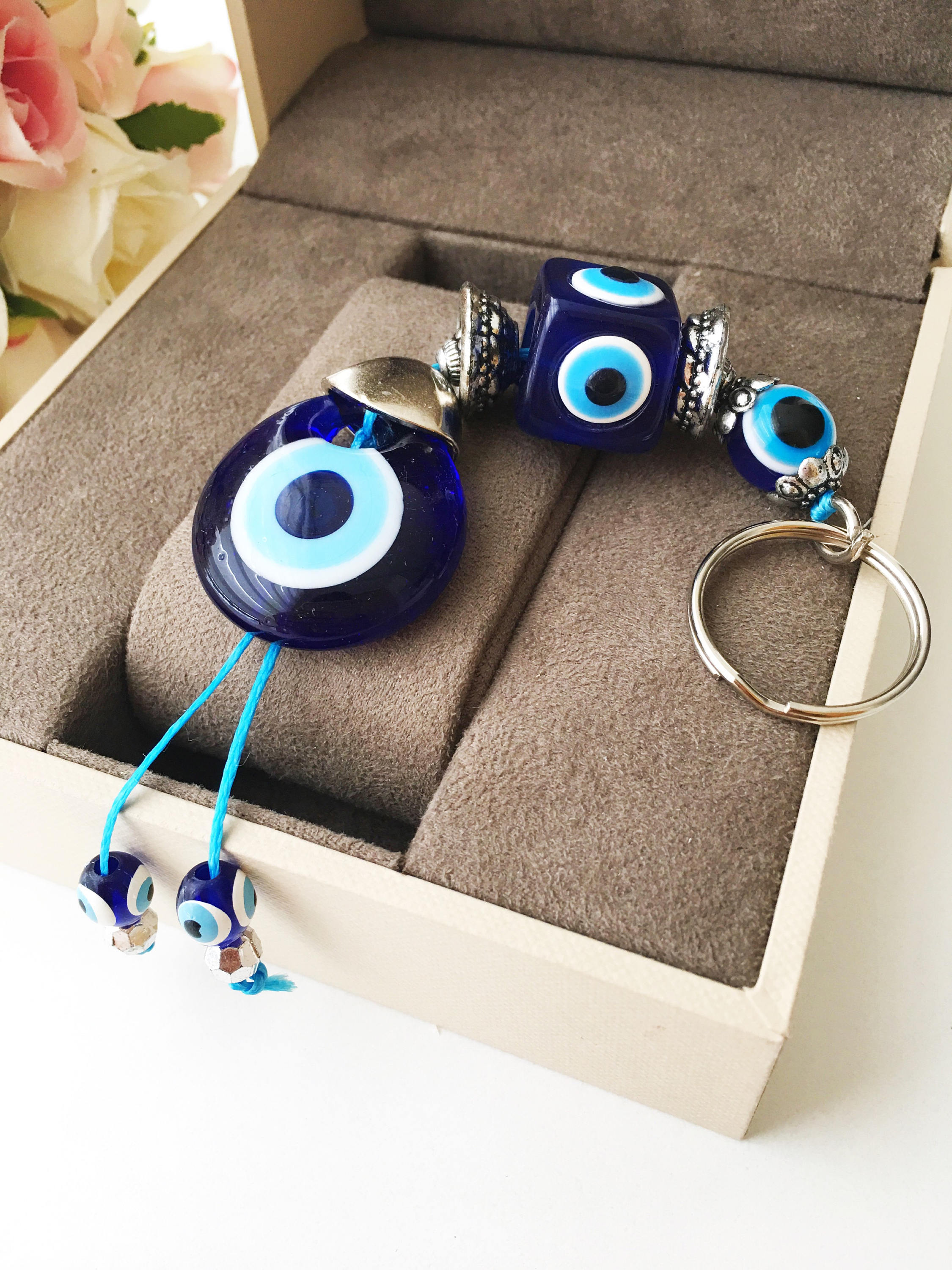 A beautifully crafted Evil Eye keychain featuring vibrant blue and white beads, symbolizing protection and good luck, attached to a silver keyring.