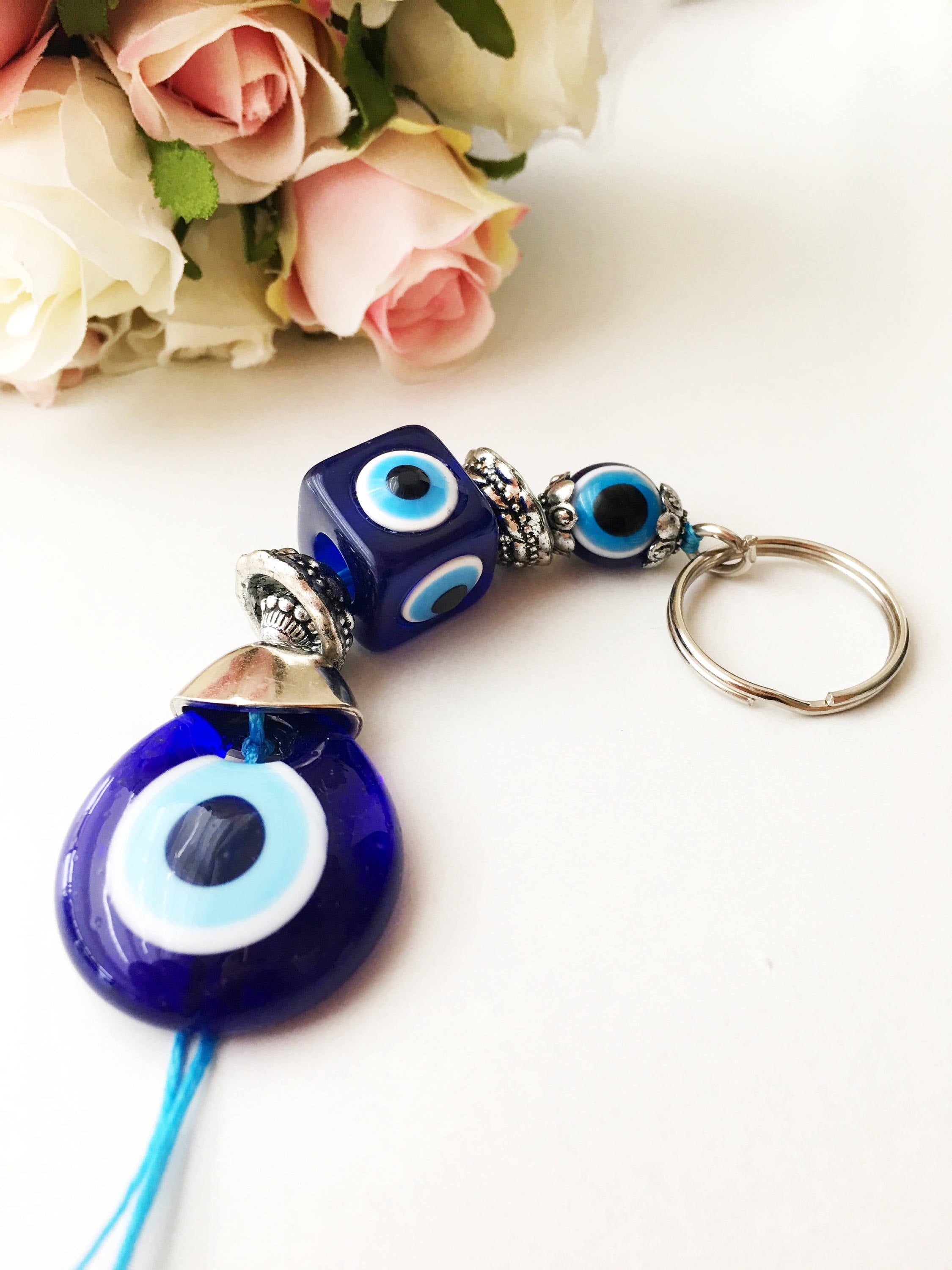 A beautifully crafted Evil Eye keychain featuring vibrant blue and white beads, symbolizing protection and good luck, attached to a silver keyring.